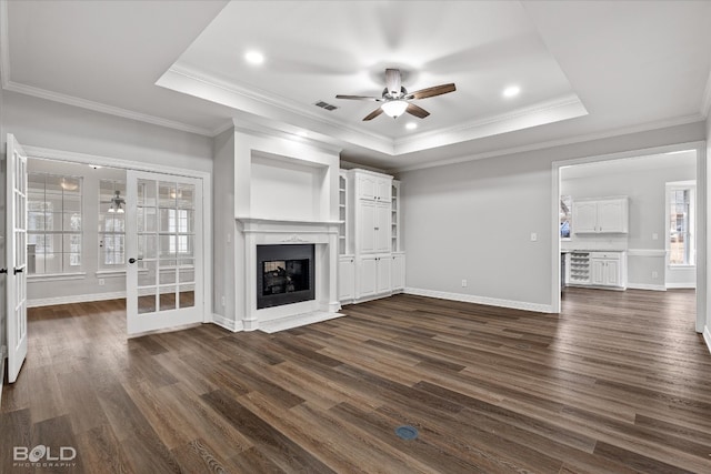 unfurnished living room with a high end fireplace, a raised ceiling, ceiling fan, and dark hardwood / wood-style flooring