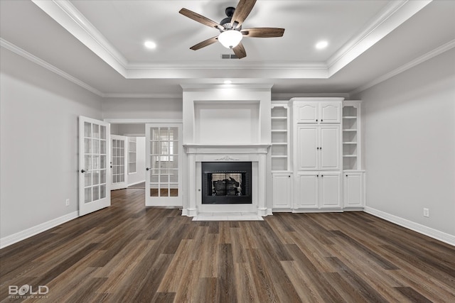 unfurnished living room featuring dark wood-type flooring, ceiling fan, crown molding, a tray ceiling, and french doors