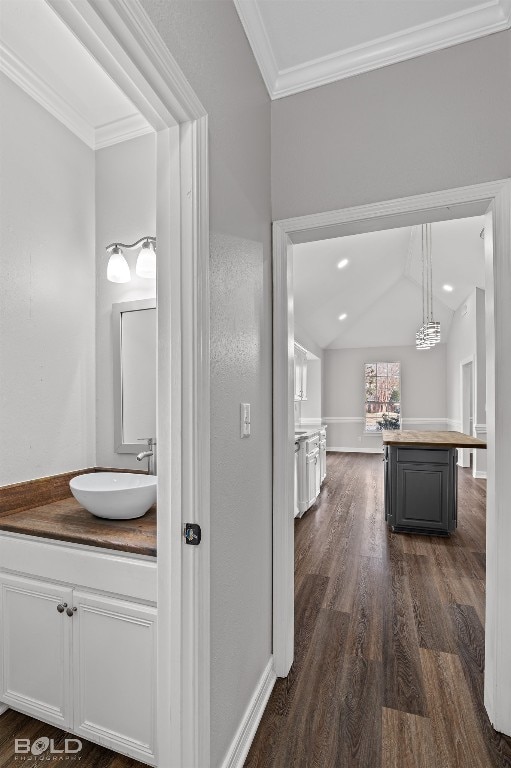 bathroom with crown molding, oversized vanity, vaulted ceiling, and hardwood / wood-style flooring