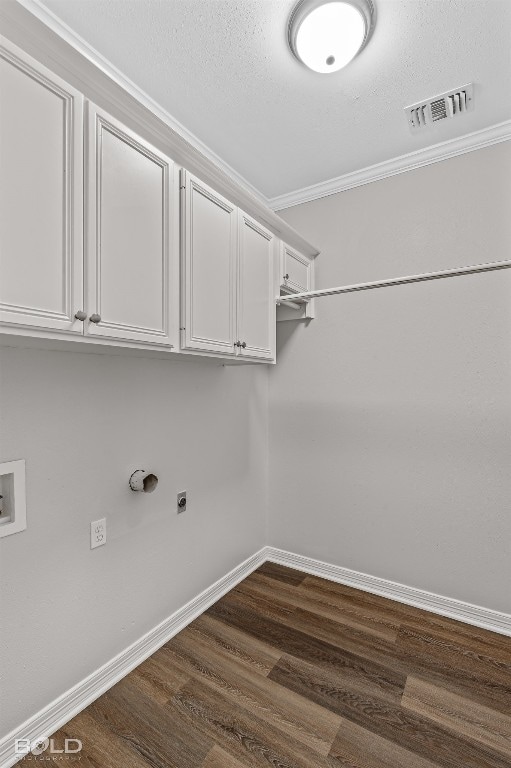 clothes washing area featuring dark hardwood / wood-style floors, washer hookup, hookup for an electric dryer, ornamental molding, and cabinets