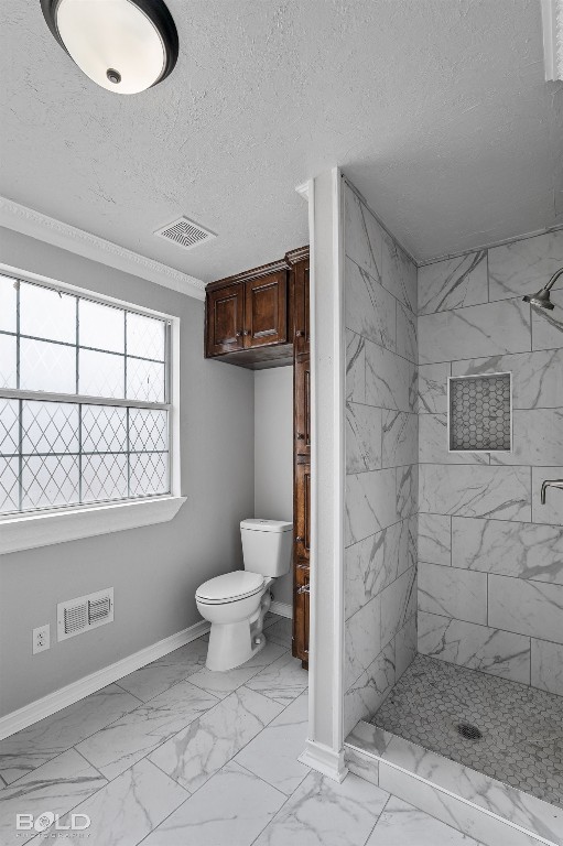 bathroom featuring tiled shower, tile floors, toilet, and a textured ceiling