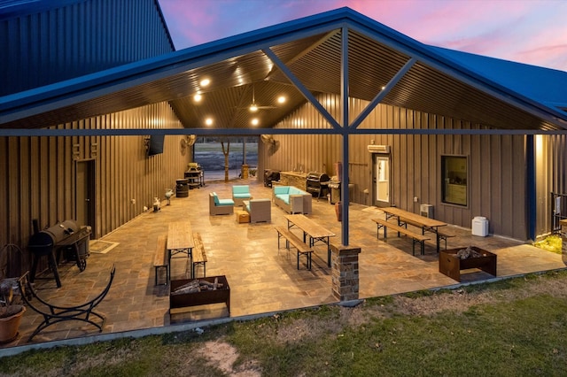 patio terrace at dusk featuring an outdoor living space with a fire pit and area for grilling