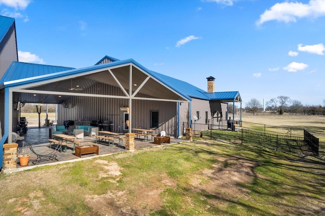 rear view of house featuring a rural view, an outdoor living space, a yard, and a patio area