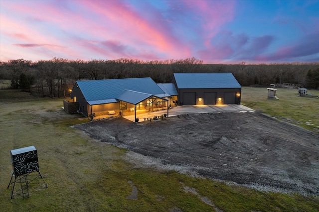 exterior space with metal roof, driveway, and a lawn