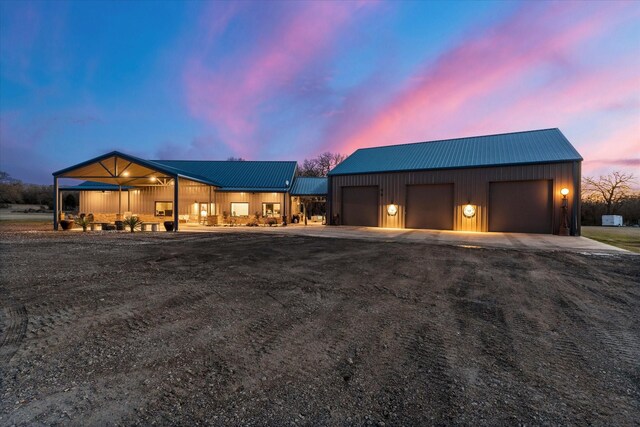 view of front of property with a garage, metal roof, and dirt driveway