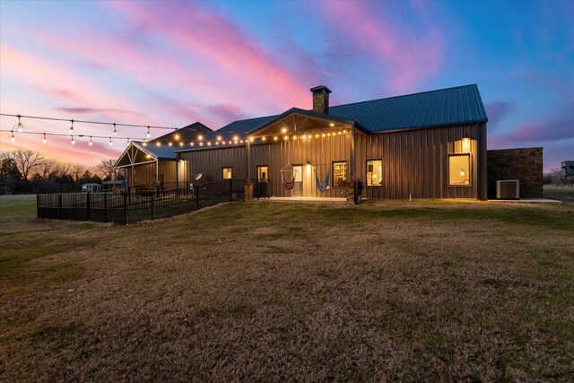 back of house featuring metal roof, a yard, board and batten siding, and central air condition unit