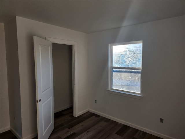 unfurnished bedroom featuring multiple windows and dark hardwood / wood-style flooring