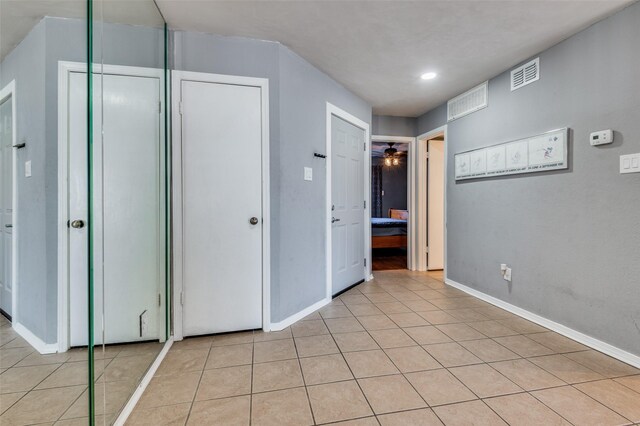 kitchen featuring stainless steel range with electric stovetop, white cabinets, light tile floors, and ceiling fan