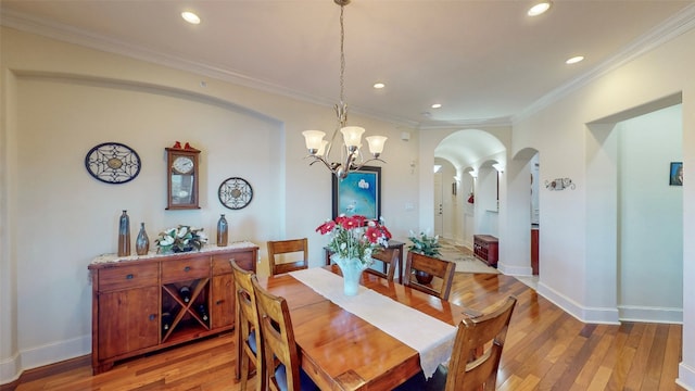 dining area featuring ornate columns, a notable chandelier, hardwood / wood-style flooring, and crown molding