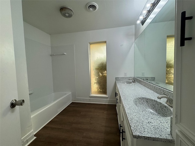 bathroom with double sink, hardwood / wood-style flooring, large vanity, and tub / shower combination