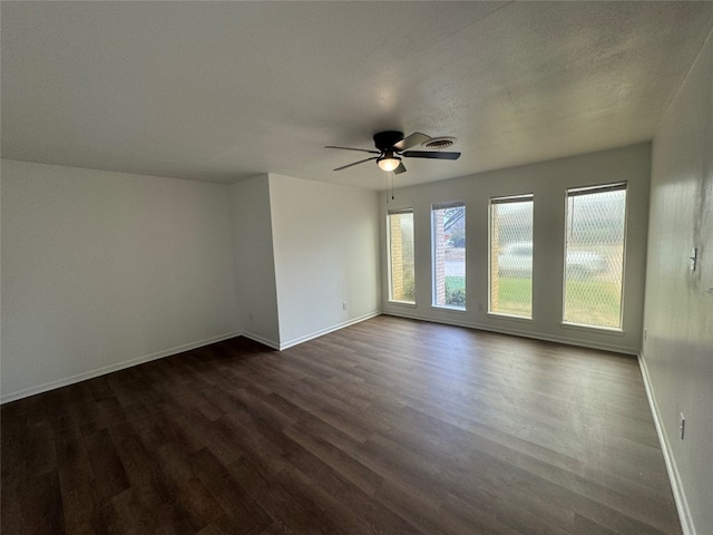 spare room with plenty of natural light, ceiling fan, and dark hardwood / wood-style flooring