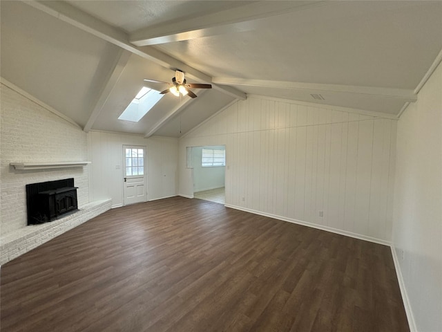 unfurnished living room with ceiling fan, dark hardwood / wood-style flooring, vaulted ceiling with skylight, and a brick fireplace