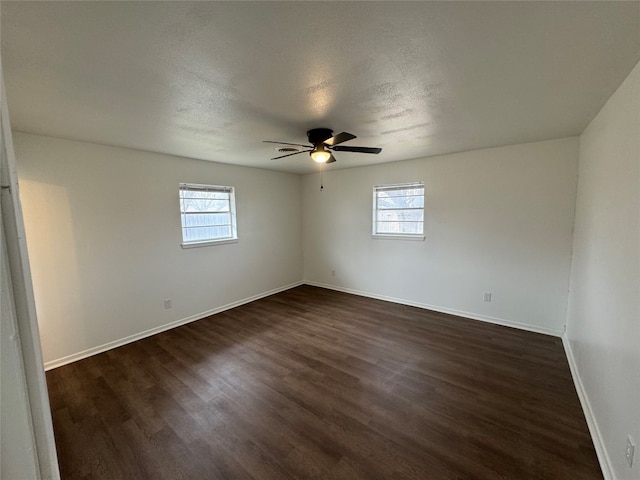 empty room with a healthy amount of sunlight, dark hardwood / wood-style flooring, and ceiling fan