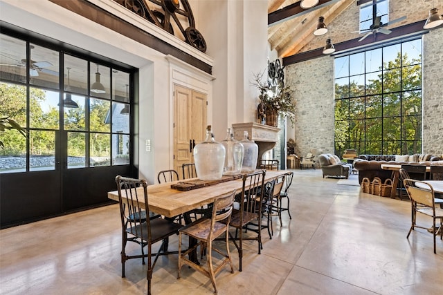 dining area with high vaulted ceiling, a fireplace, beam ceiling, and ceiling fan