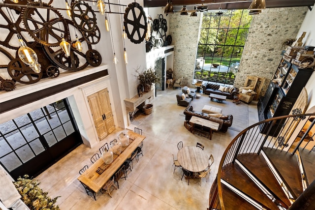 tiled living room featuring a notable chandelier, track lighting, a wall of windows, and a towering ceiling