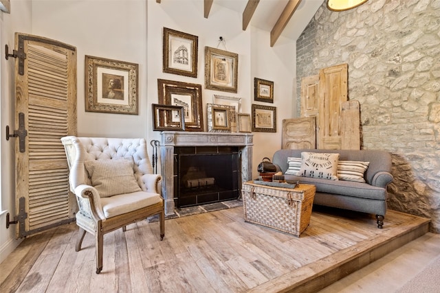 sitting room with hardwood / wood-style floors, a high ceiling, and beam ceiling