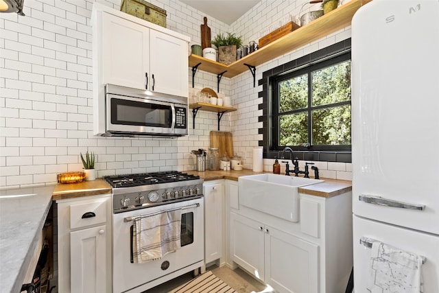 kitchen with white appliances, white cabinetry, tasteful backsplash, and sink