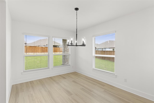 unfurnished dining area featuring a notable chandelier and light wood-type flooring