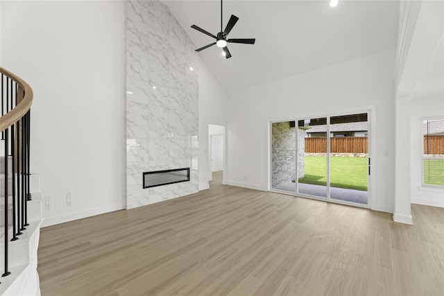 unfurnished living room with high vaulted ceiling, a fireplace, ceiling fan, and light hardwood / wood-style flooring