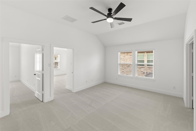 empty room featuring ceiling fan, vaulted ceiling, and light colored carpet