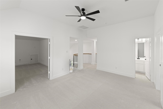 empty room with sink, ceiling fan, vaulted ceiling, and light colored carpet