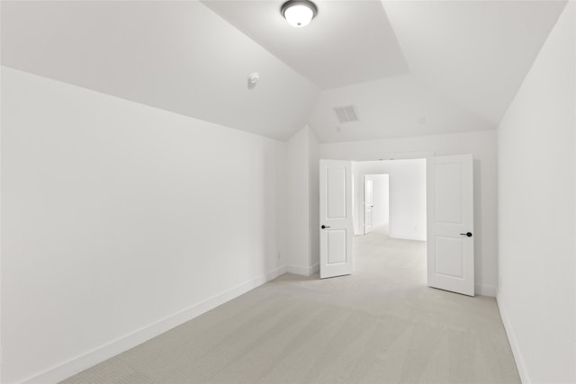 bonus room with vaulted ceiling and light colored carpet