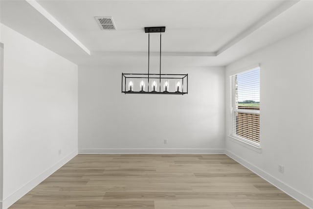 spare room with light hardwood / wood-style floors and an inviting chandelier