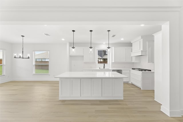 kitchen featuring white cabinetry, a center island, sink, and light hardwood / wood-style floors