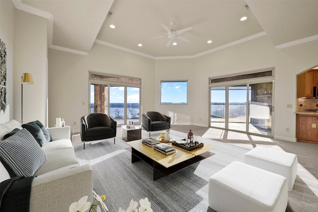 carpeted living room featuring ceiling fan, ornamental molding, and a high ceiling