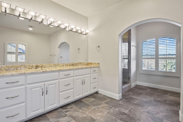 bathroom featuring vanity, a healthy amount of sunlight, and walk in shower