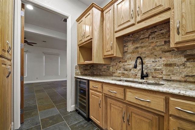 kitchen with backsplash, sink, ceiling fan, light stone counters, and beverage cooler