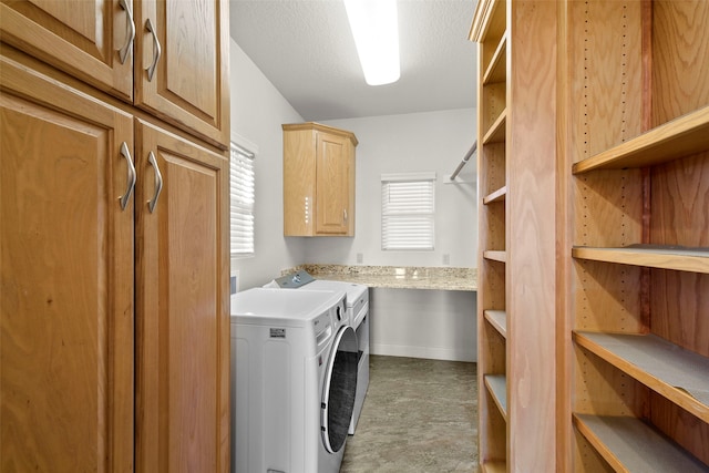 laundry area featuring cabinets, a textured ceiling, a wealth of natural light, and washing machine and clothes dryer