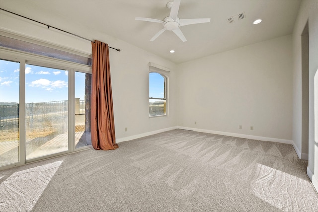 empty room featuring carpet, ceiling fan, and a wealth of natural light