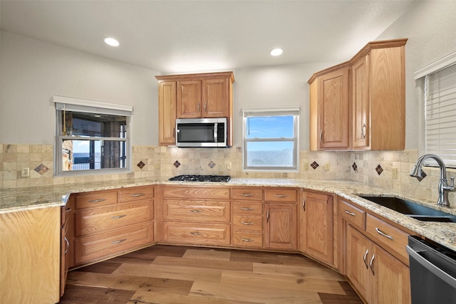 kitchen featuring decorative backsplash, sink, light hardwood / wood-style flooring, and appliances with stainless steel finishes