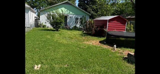 view of yard featuring a trampoline and a storage shed