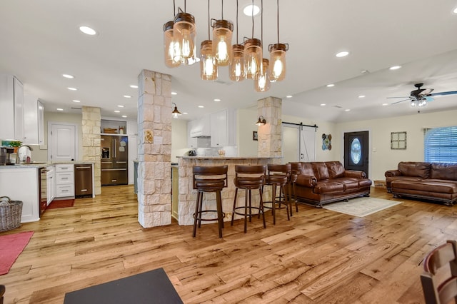 interior space featuring white cabinetry, a barn door, kitchen peninsula, light hardwood / wood-style floors, and high quality fridge