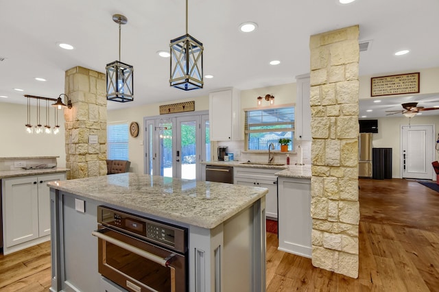 kitchen with decorative columns, light hardwood / wood-style flooring, a kitchen island, and decorative light fixtures