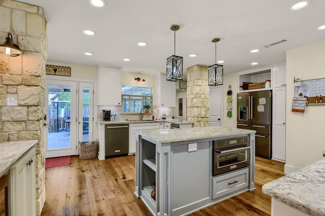 kitchen featuring white cabinetry, a kitchen island, stainless steel appliances, and decorative light fixtures