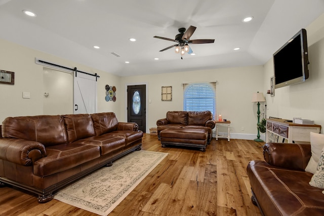 living room with a barn door, light hardwood / wood-style flooring, and ceiling fan