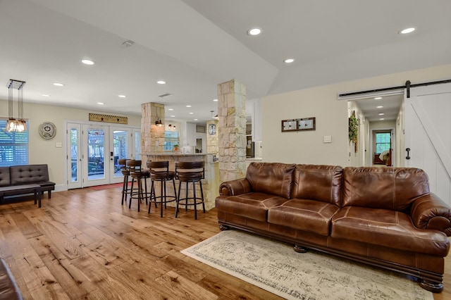 living room with plenty of natural light, a barn door, lofted ceiling, and light hardwood / wood-style flooring