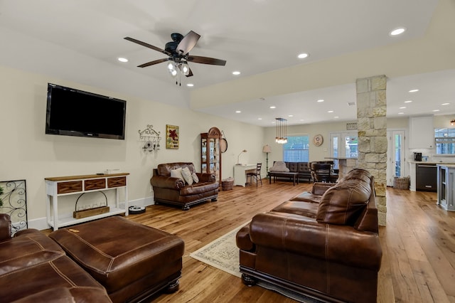 living room featuring decorative columns, ceiling fan, and light wood-type flooring