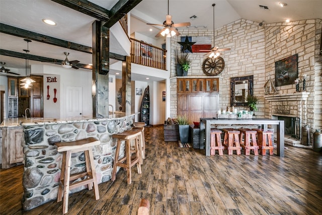 kitchen featuring ceiling fan, a fireplace, high vaulted ceiling, dark hardwood / wood-style flooring, and pendant lighting