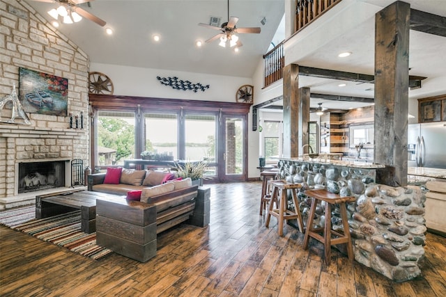 living room featuring dark hardwood / wood-style floors, ceiling fan, a fireplace, and high vaulted ceiling