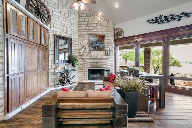 living room featuring dark wood-type flooring, ceiling fan, high vaulted ceiling, and a fireplace