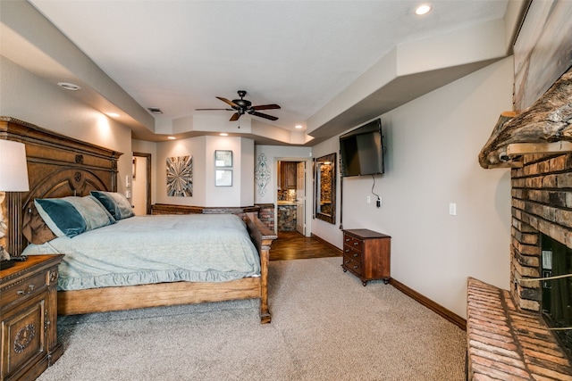 carpeted bedroom with ceiling fan and a brick fireplace