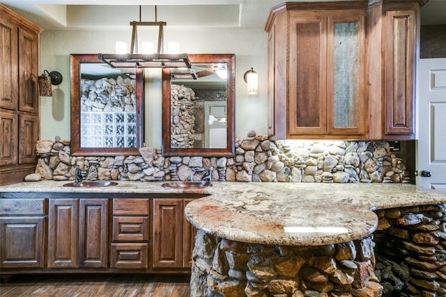 kitchen featuring light stone countertops, a kitchen bar, tasteful backsplash, dark hardwood / wood-style flooring, and pendant lighting