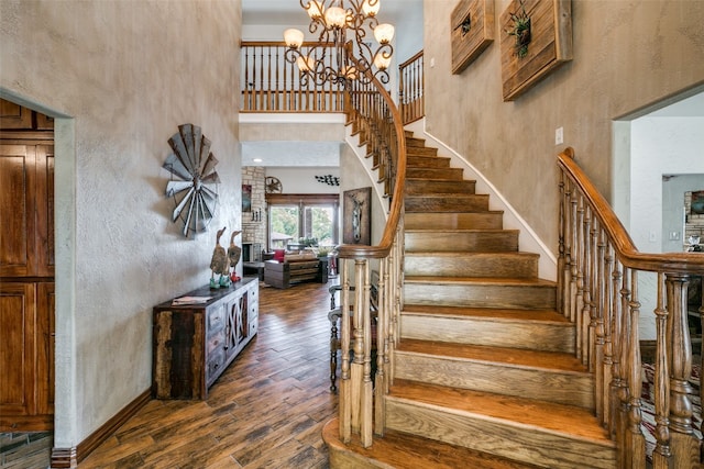 stairway featuring an inviting chandelier, dark hardwood / wood-style flooring, and a high ceiling