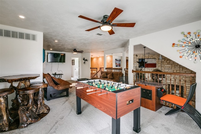 rec room with brick wall, ceiling fan, and light colored carpet