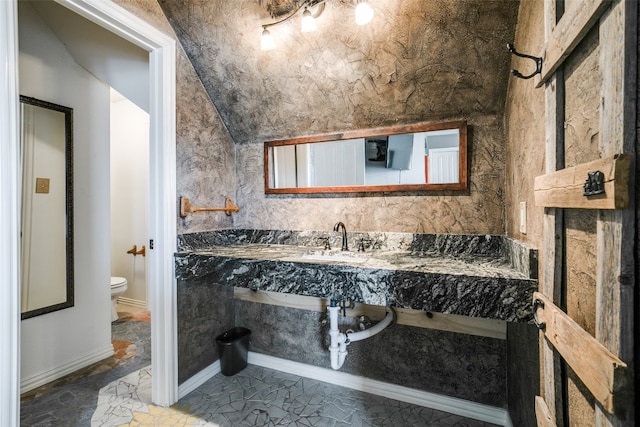 bathroom with lofted ceiling, toilet, tile floors, and sink