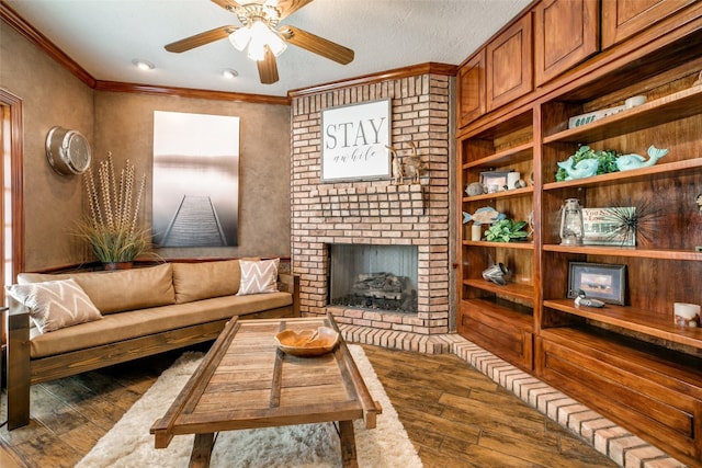 living room with brick wall, a brick fireplace, dark hardwood / wood-style flooring, and ceiling fan